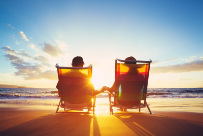 two people in beach chairs sitting on the beach in front of the sunset